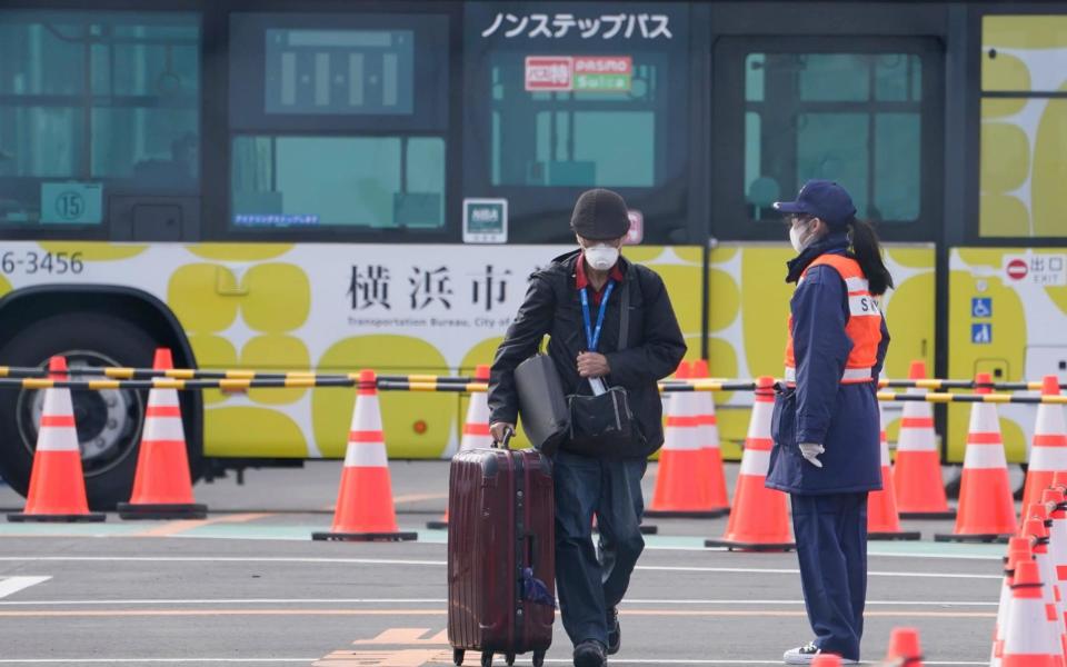 A passenger of the Diamond Princess cruise ship leaves the Daikoku Pier Cruise Terminal in Yokohama - Rex