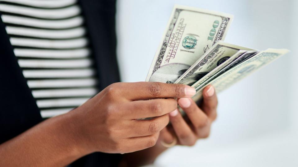 Cropped shot of an unrecognizable businesswoman counting money inside her office at work.