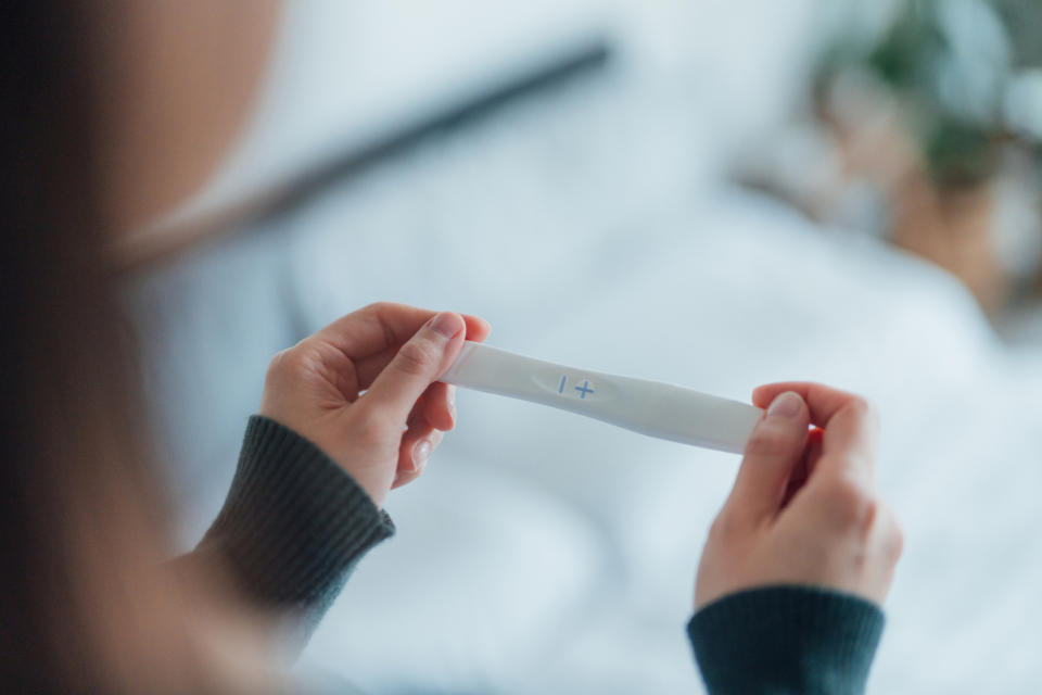 Person holding a home pregnancy test showing a positive result