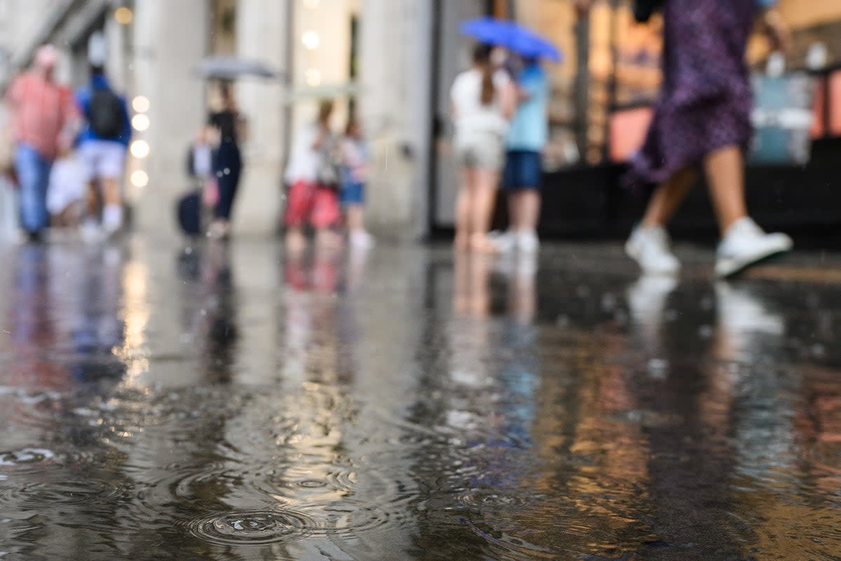 Raindrops land in a puddle as shoppers rush through a heavy downpour on August 16, 2022 in London, England (Getty)