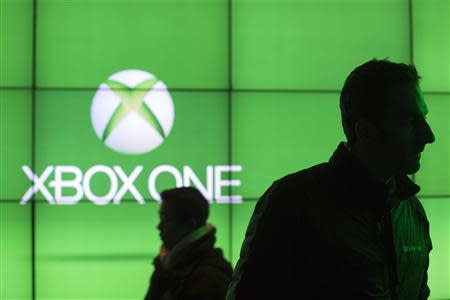 People walk in front of a screen advertising the Xbox One at an event celebrating the console's midnight launch in New York November 21, 2013. REUTERS/Lucas Jackson