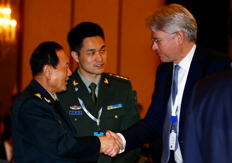 Chinese Defense Minister Wei Fenghe shakes hands with CEO of BAE Systems Charles Woodburn at the the IISS Shangri-la Dialogue in Singapore