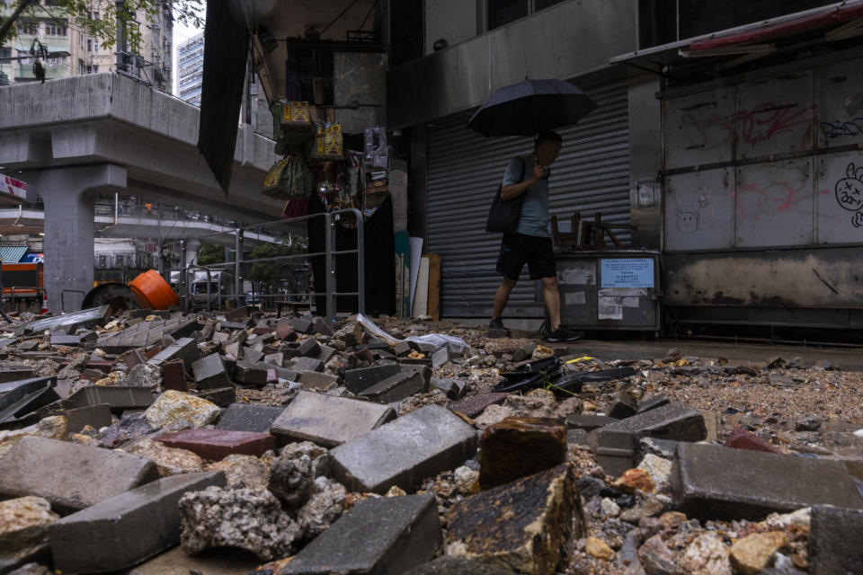 A pedestrian passes through debris following heavy rainstorms in Hong Kong, Friday, Sept. 8, 2023. (AP Photo/Louise Delmotte)