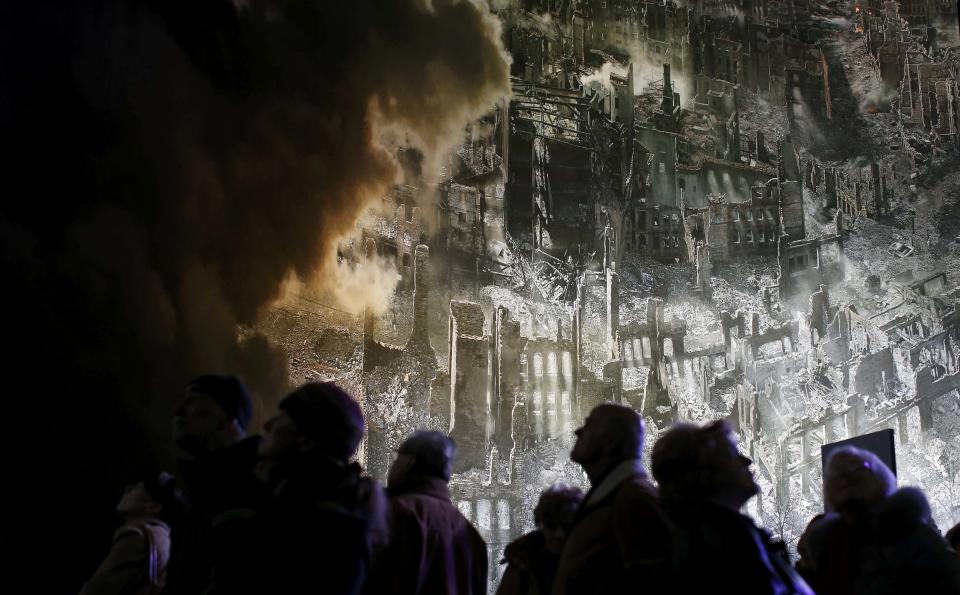 People are silhouetted as they watch the 'Dresden 1945' 360 degrees panorama showing the destroyed city of Dresden after the bombing raids during the World War Two in February 1945 at the Panometer in Dresden