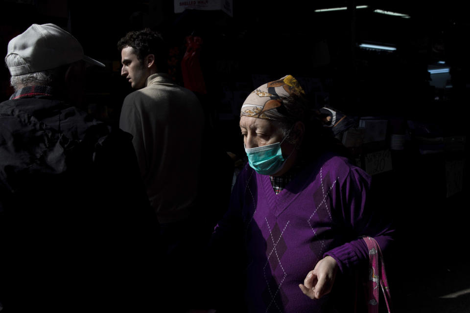 An elderly woman wears a face mask as she shops at a food market in Tel Aviv, Israel, March 15, 2020. (AP Photo/Oded Balilty)