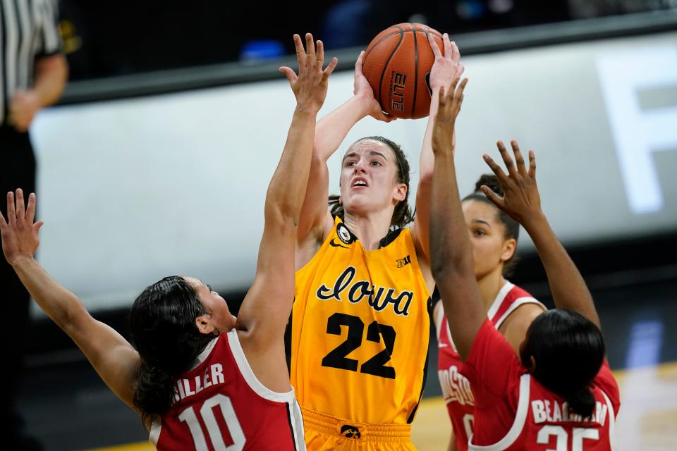 Iowa guard Caitlin Clark (22) drives to the basket between Ohio State guard Braxtin Miller (10) and forward Tanaya Beacham, right, during the first half of an NCAA college basketball game, Wednesday, Jan. 13, 2021, in Iowa City, Iowa. (AP Photo/Charlie Neibergall)