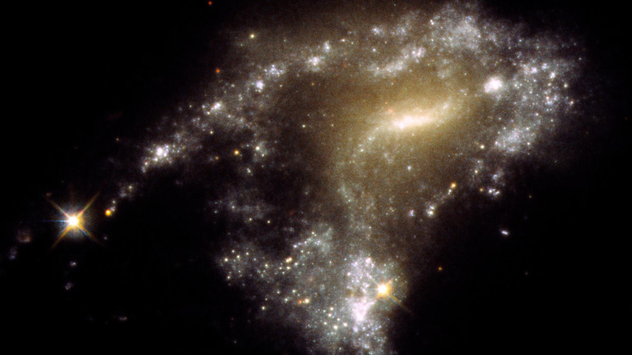  Blurry sparkles of white and yellow cluster to form a blurry galaxy. 