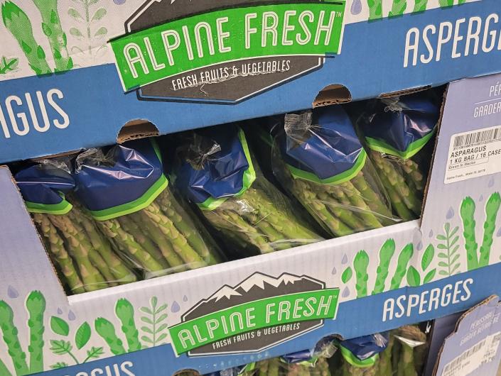 Packages of asparagus in cardboard boxes in grocery store