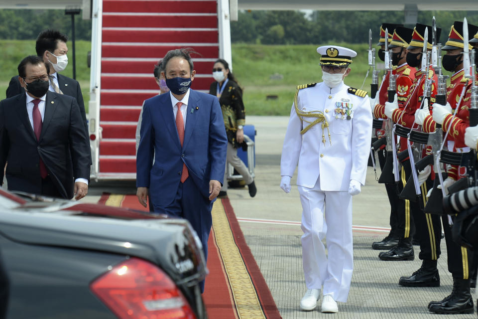 In this photo released by Indonesian Presidential Palace, Japanese Prime Minister Yoshihide Suga, center, walks to his car upon arrival at Halim Perdanakusuma Airport in Jakarta, Indonesia, Tuesday, Oct. 20, 2020. Suga arrived in Indonesia on the second leg of his first overseas trip as premier to underscore his government’s aims of countering China in the region. (Indonesian Presidential Palace via AP)