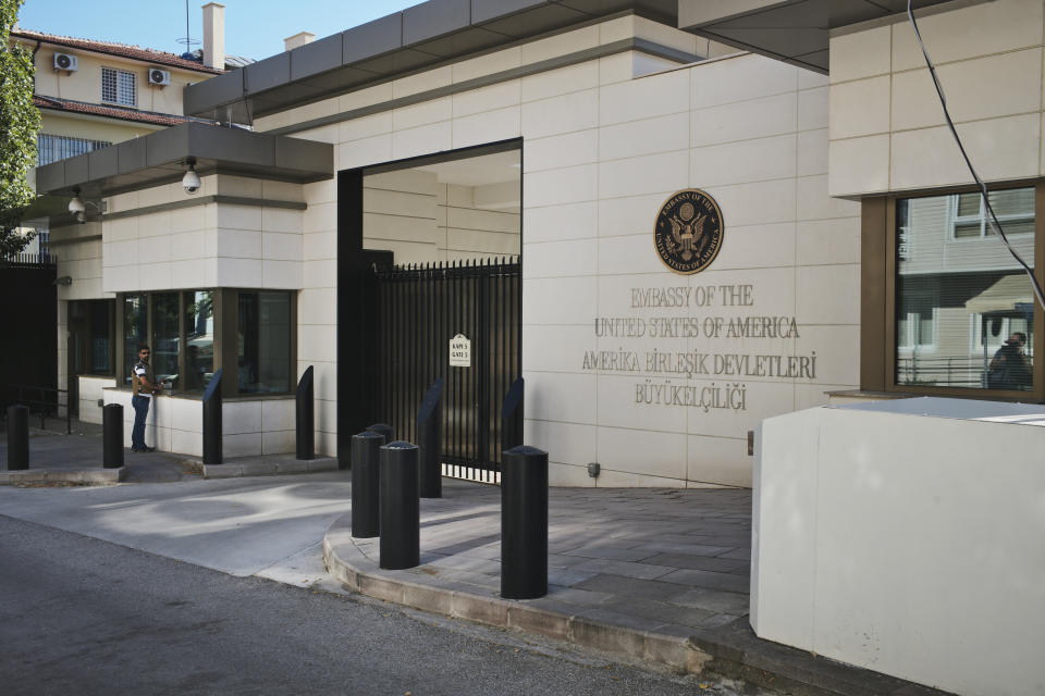 A security guard stands outside the entrance to the U.S. Embassy in Ankara, Turkey, Monday, Aug. 20, 2018. Shots were fired at a security booth outside the embassy in Turkey's capital early Monday, but U.S. officials said no one was hurt. Ties between Ankara and Washington have been strained over the case of an imprisoned American pastor, leading the U.S. to impose sanctions, and increased tariffs that sent the Turkish lira tumbling last week. (AP Photo/Burhan Ozbilici)