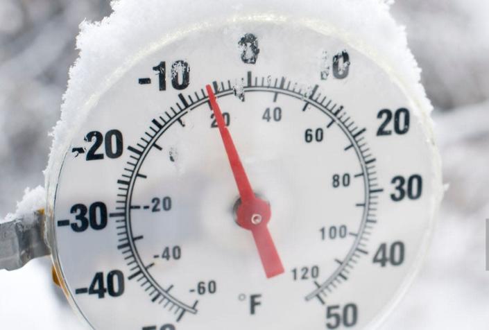 A thermometer showing freezing temperatures and falling snow.