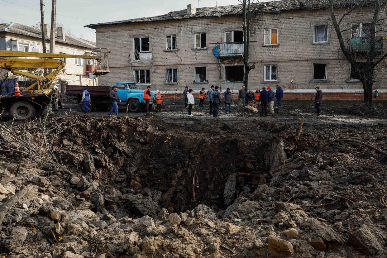 Local services workers remove debris near the crater, after a Russian missile strike at the site of damaged residential houses. (REUTERS)