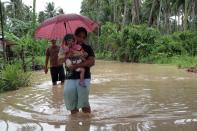 A woman carrying her child wades through a flooded road brought about by heavy rains due to Typhoon Bopha, as she evacuates to a safer place, in Pantukan town on the southern island of Mindanao. At least 274 people have been killed and hundreds remain missing in the Philippines from the deadliest typhoon to hit the country this year, according to the civil defence chief