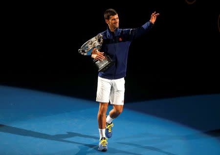 Serbia's Novak Djokovic waves as he walks with the men's singles trophy after winning his final match against Britain's Andy Murray at the Australian Open tennis tournament at Melbourne Park, Australia, January 31, 2016. REUTERS/Brandon Malone