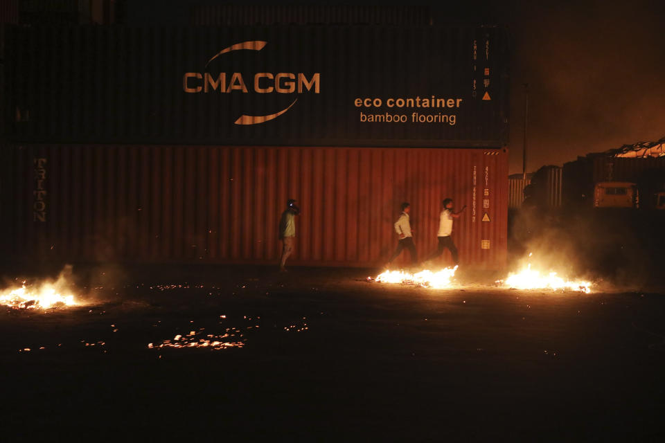 Unidentified men run after a fire broke out at the BM Inland Container Depot, a Dutch-Bangladesh joint venture, in Chittagong, 216 kilometers (134 miles) southeast of capital, Dhaka, Bangladesh, early Sunday, June 5, 2022. Several people were killed and more than 100 others were injured in the fire the cause of which could not be immediately determined. (AP Photo)
