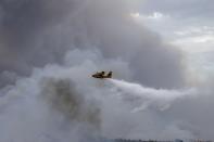 <p>A firefighting plane empties the water over the flame after a fire broke out at forested land in Penteli town of Athens, Greece on July 23, 2018. (Photo: Ayhan Mehmet/Anadolu Agency/Getty Images) </p>