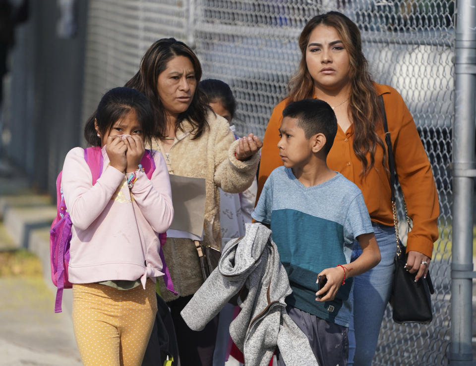 A girl covers her mouth and nose as parents and children leave school after jet fuel was dumped on Park Avenue Elementary School in Cudahy, Calif., Tuesday, Jan. 14, 2020. Jet fuel dumped by an aircraft returning to Los Angeles International Airport fell onto the school playground where children were playing Tuesday, fire officials said. The Los Angeles County Fire Department said firefighters assessed over a dozen children and several adults who complained of minor injuries and none needed to be taken to a hospital. (Scott Varley/The Orange County Register via AP)