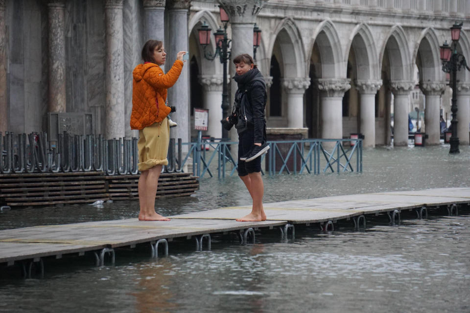 Tourists stand on a trestle bridge as high water floods Venice, northern Italy, Sunday, Nov. 24, 2019. The high water reached peak of 135cm (4.42ft) early Sunday. (Andrea Merola/ANSA via AP)