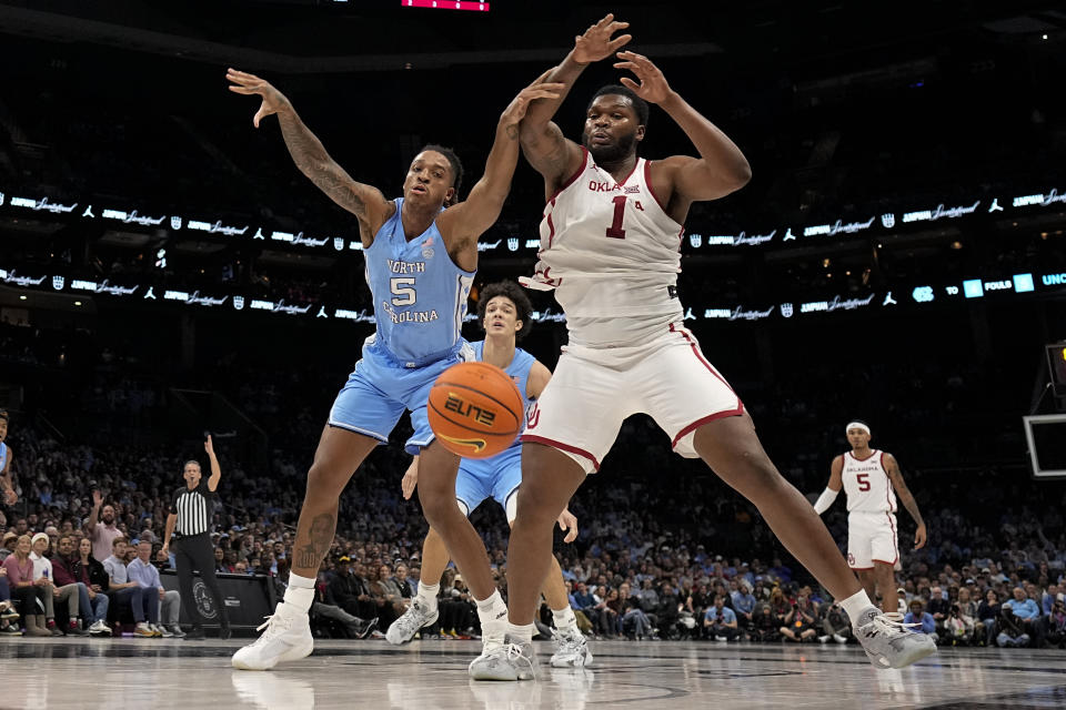 North Carolina forward Armando Bacot, left, vies for the ball with Oklahoma forward John Hugley IV during the first half of an NCAA college basketball game Wednesday, Dec. 20, 2023, in Charlotte, N.C. (AP Photo/Chris Carlson)