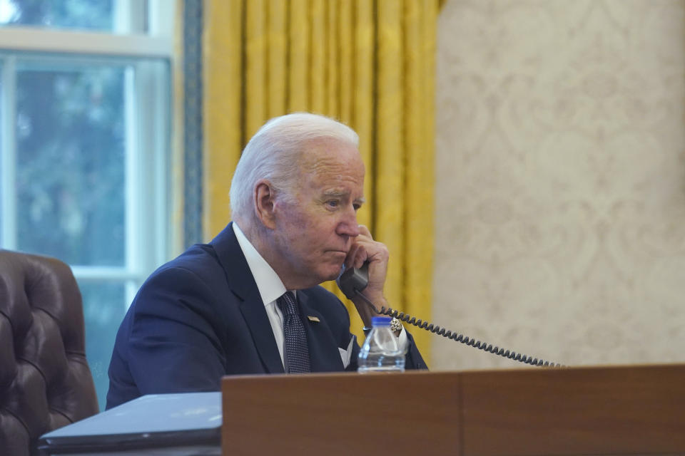 In this image made through a window, President Joe Biden talks on the phone with Ukrainian President Volodymyr Zelenskyy from the Oval Office of the White House in Washington, Thursday, Dec. 9, 2021. (AP Photo/Susan Walsh)