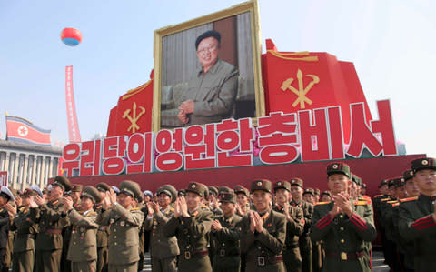 Soldiers applaud during an event marking the 20th anniversary of the election of former North Korean leader Kim Jong Il, in portrait - Credit: AP Photo/Jon Chol Jin