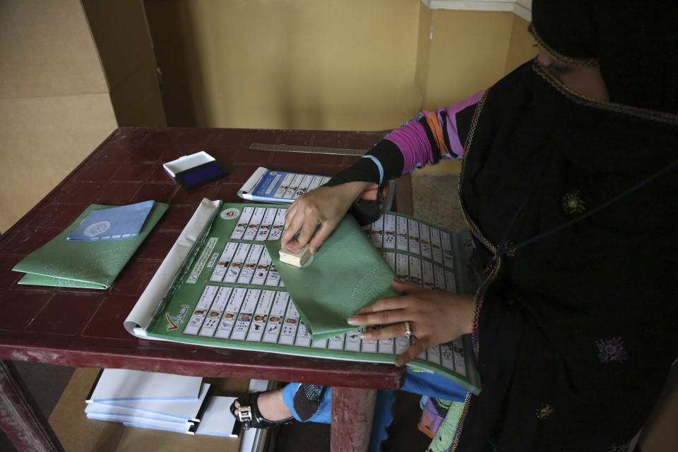 An Afghan election worker stamps a ballot before giving it to a voter, at a polling station in Jalalabad east of Kabul, Afghanistan, Saturday, April 5, 2014. Afghan voters lined up for blocks at polling stations nationwide on Saturday, defying a threat of violence by the Taliban to cast ballots in what promises to be the nation's first democratic transfer of power. (AP Photo/Rahmat Gul)