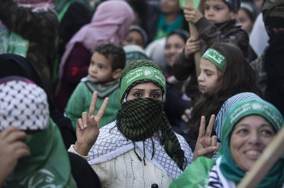 A Palestinian woman flashes the victory sign and wears a headband with Arabic that reads: "No God but Allah and Muhammed is his messenger, al-Qassam Brigades" during a mass rally marking the 32nd anniversary of the founding of Hamas, an Islamic political party that currently rules in Gaza, Saturday, Dec. 14, 2019, in Gaza city. (AP Photo/Khalil Hamra)