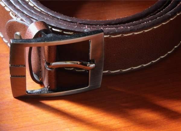 Closeup view of a brown leather belt with metal buckle