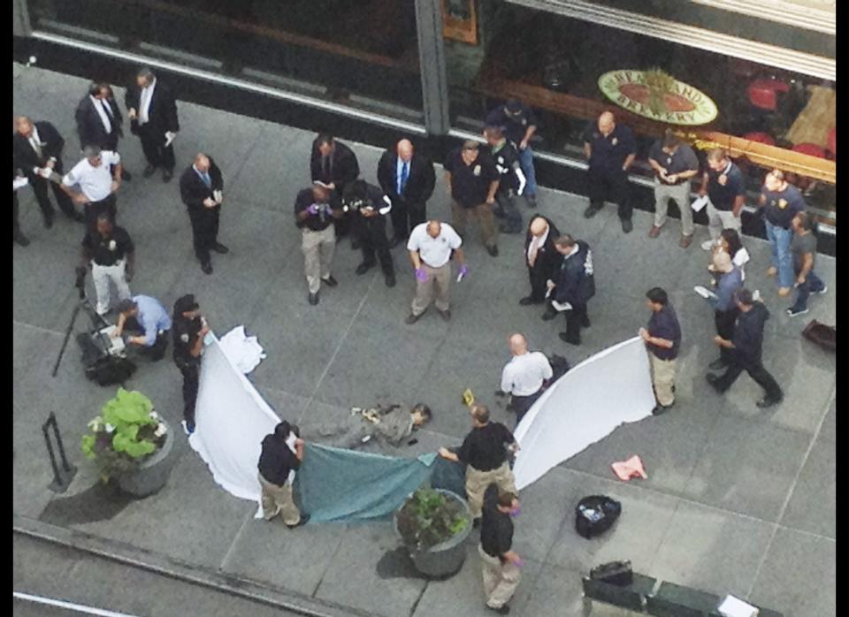 In this photo made with a cell phone, officials examine the body of gunman Jeffrey Johnson, who was killed by police gunfire after he fatally shot Steven Ercolino, an executive at his former company, outside the Empire State Building, Friday, Aug. 24, 2012, in New York. At least nine bystanders were hit by gunfire in the confrontation. (AP Photo/Lee Weinstein)