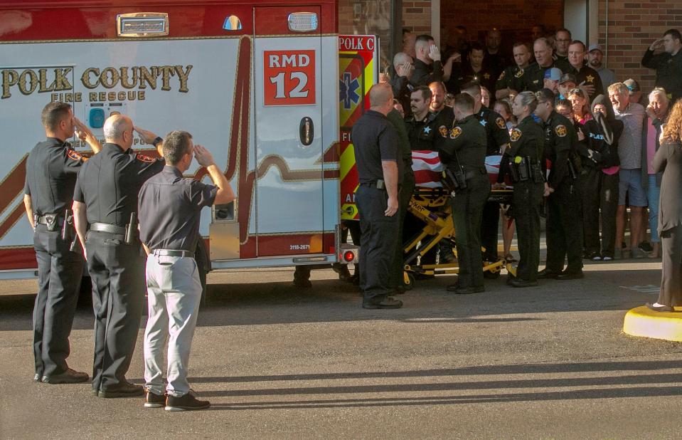 Polk County Sheriff's Deputy Blane Lane, 21, is placed in an ambulance at Lakeland Regional Health Medical Center on Tuesday as law officials and family mourn.