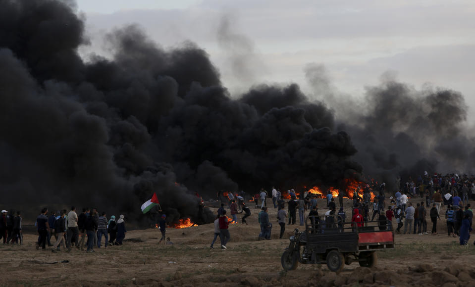 Protesters gather while others burn tires near the fence of the Gaza Strip border with Israel during a protest east of east of Gaza City, Friday, Oct. 26, 2018. (AP Photo/Adel Hana)