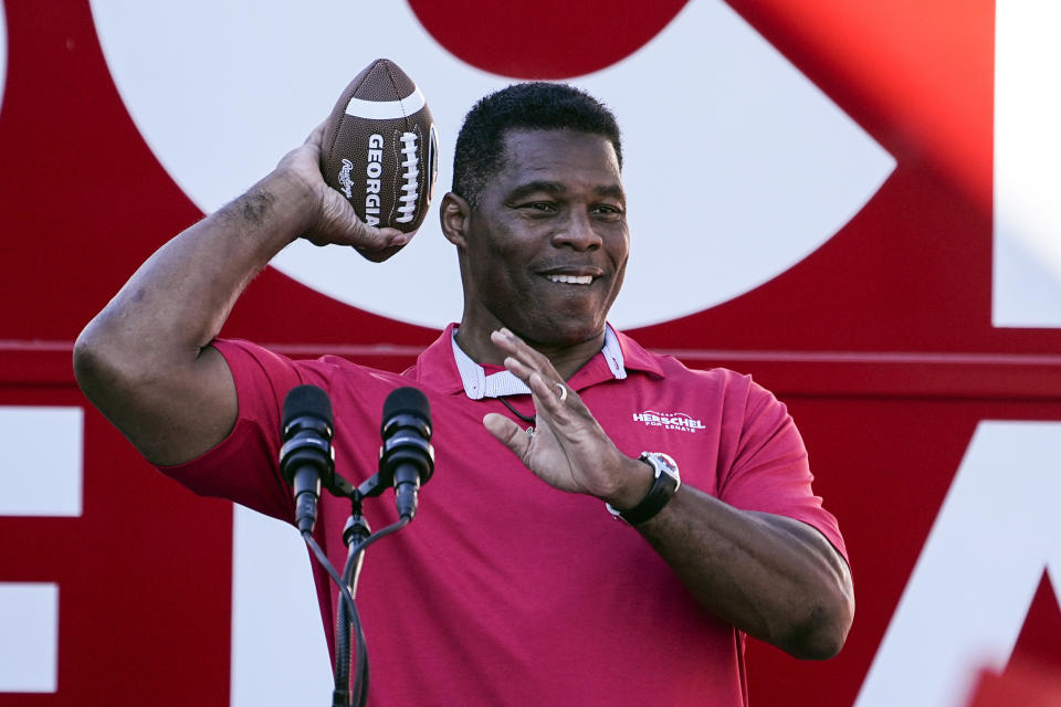 FILE - Republican candidate for U.S. Senate Herschel Walker throws a football to a supporter during a campaign rally Nov. 29, 2022, in Greensboro, Ga. Walker is in a runoff election with incumbent Democratic Sen. Raphael Warnock. (AP Photo/John Bazemore, File)