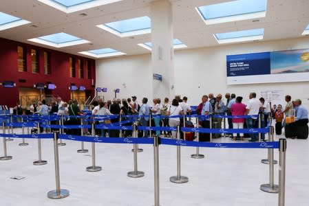 People line up in front of a counter at Chania Airport after Thomas Cook, the world's oldest travel firm collapsed