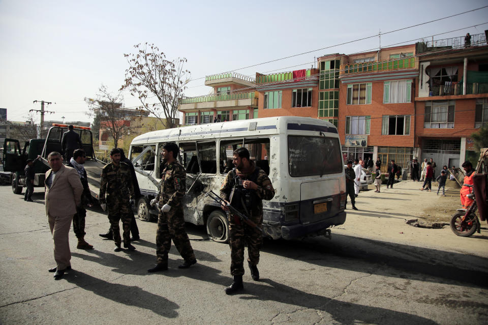 Security personnel inspect a damaged minibus after a bomb explosion in Kabul, Afghanistan, Thursday, March 18, 2021. The bus attack caused numerous deaths and injuries according to police. (AP Photo/Mariam Zuhaib)