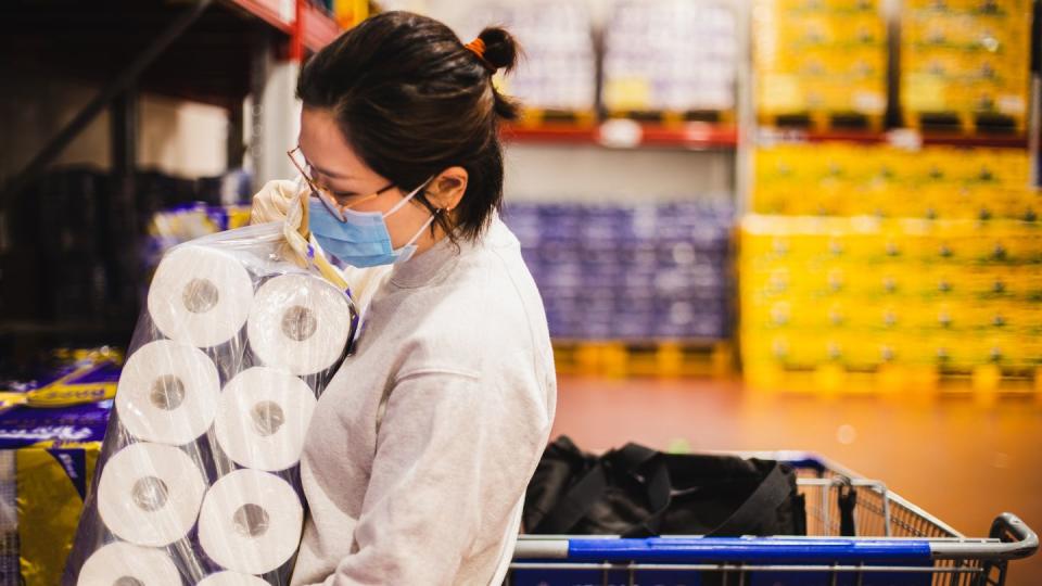 asian female wearing a face mask choosing toilet paper