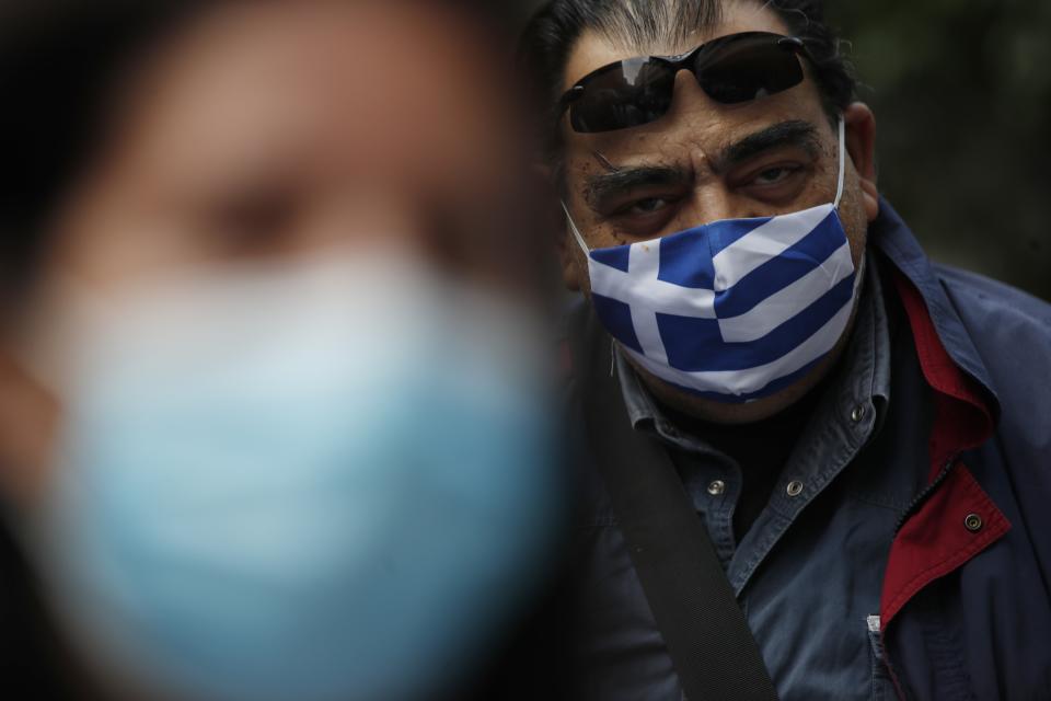 A retired health worker wearing a face mask with the Greek flag, takes part in a protest at Evangelismos hospital in Athens, Thursday, Nov. 12, 2020. State health workers' union staged protests at several hospitals around the country to demand more hiring. Greece has imposed a nationwide nightly curfew as the number of COVID-19 cases in the country continues to surge despite a lockdown. (AP Photo/Thanassis Stavrakis)