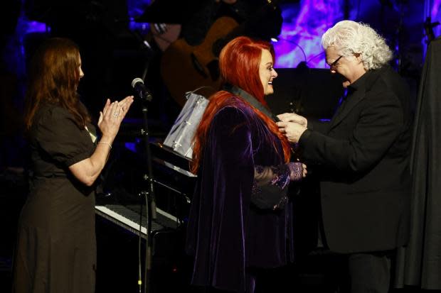 Ricky Skaggs presents Wynonna Judd with her medallion during the Medallion Ceremony at the Country Music Hall of Fame as sister Ashley Judd, left, looks on Sunday, May 1, 2022, in Nashville, Tenn. (Photo by Wade Payne/Invision/AP).