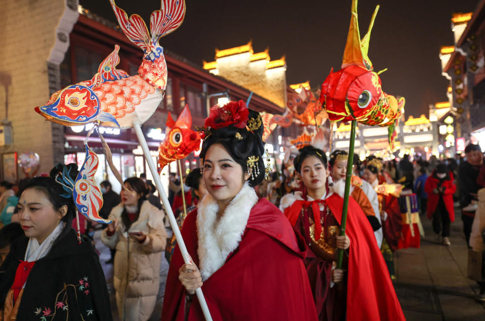 People dressed in traditional hanfu costumes hold fish lanterns during the Lantern Festival at Xiangyang in Hubei province of China, Feb. 5, 2023.