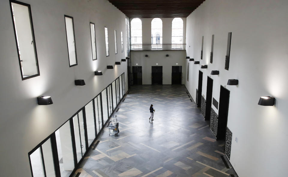 A cleaner walks in an empty corridor of the Statale University in Milan, Italy, Thursday, March 5, 2020. Italy's virus outbreak has been concentrated in the northern region of Lombardy, but fears over how the virus is spreading inside and outside the country has prompted the government to close all schools and Universities nationwide for two weeks. (AP Photo/Antonio Calanni)