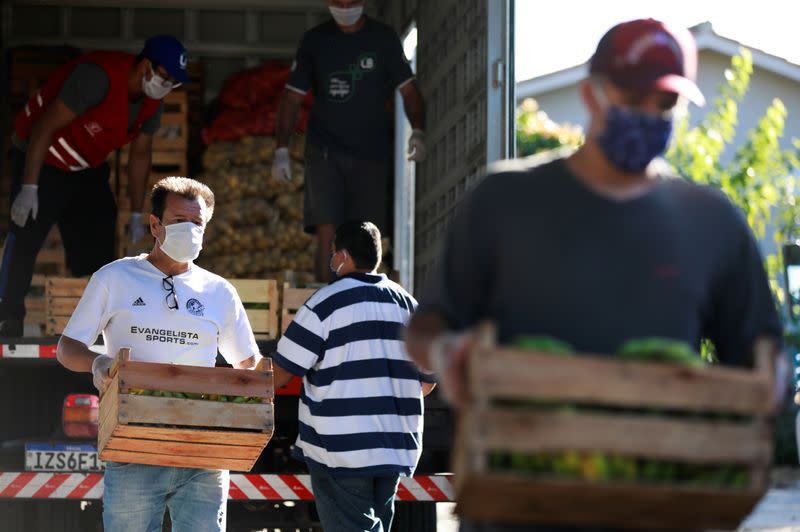 El capitán de la Copa del Mundo en 1994 y ex entrenador de fútbol de Brasil Dunga, el jugador del club de fútbol Internacional Andrés D'Alessandro y el ex jugador de fútbol Tinga ayudan con la distribución de alimentos a las personas pobres, en Porto Alegre, Brasil, el 7 de abril de 2020