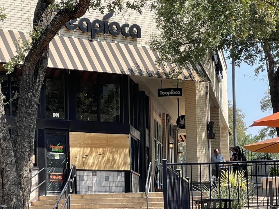 A broken window is covered in plywood at Teapioca shop at the Arboretum on Friday after a fatal shooting on Thursday.