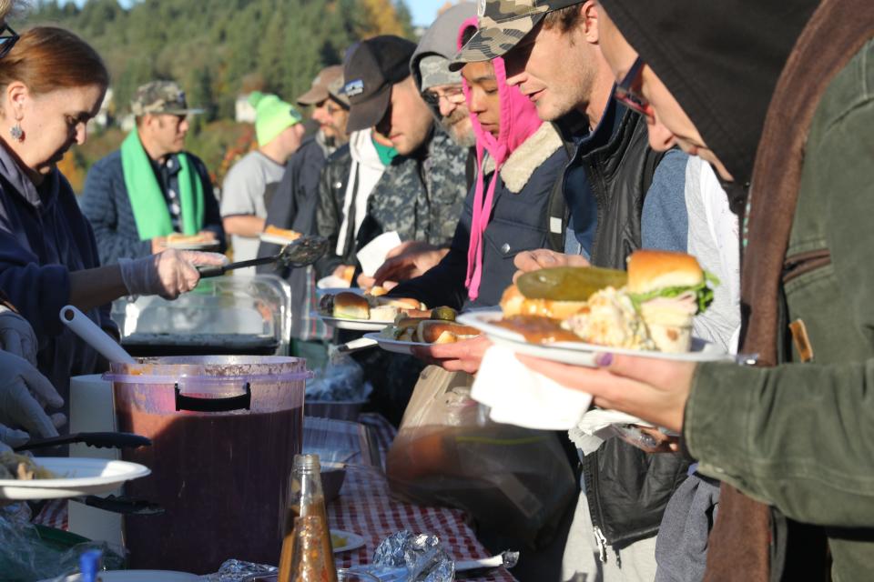 Volunteers serve food to a line of attendees at a community picnic on Sunday, Oct. 27. Kimmy Siebens, a local homeless advocate, started the free meals a few years ago, serving hotdogs and beans out of the bed of her truck.