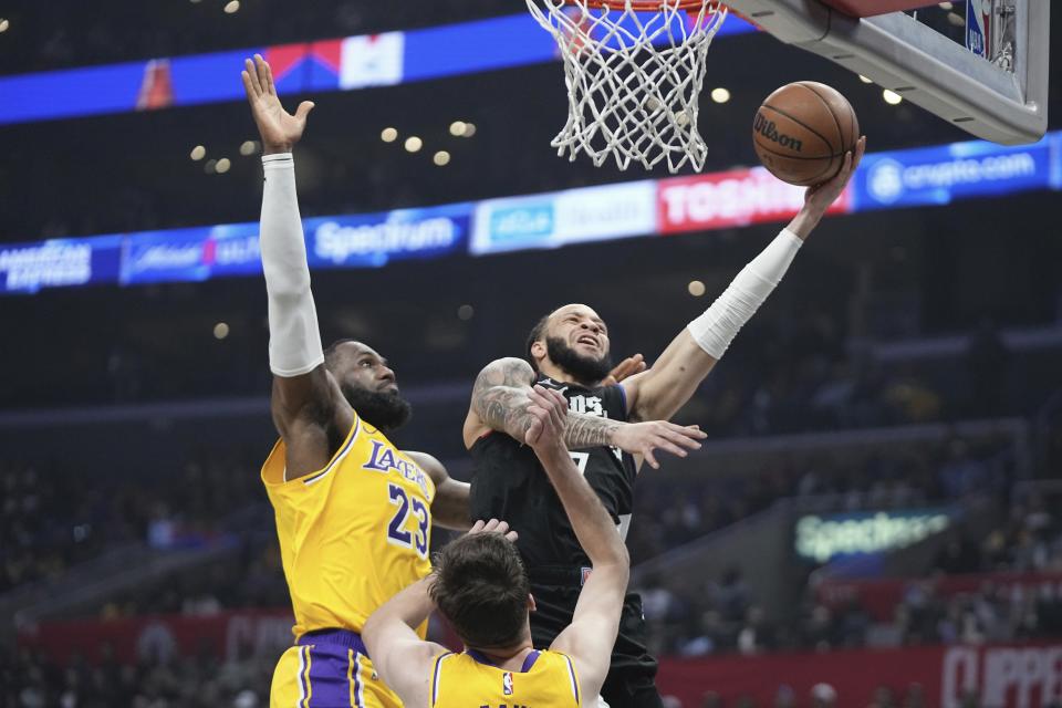 Los Angeles Clippers guard Amir Coffey, right, shoots as Los Angeles Lakers forward LeBron James, left, and guard Austin Reaves defend during the first half of an NBA basketball game Wednesday, Feb. 28, 2024, in Los Angeles. (AP Photo/Mark J. Terrill)