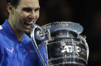 Spain's Rafael Nadal bits the ATP World Number 1 trophy as he poses for photographs following the presentation on court after his match against Stefanos Tsitsipas of Greece at the ATP World Tours Finals in the O2 Arena in London, Friday, Nov. 15, 2019. (AP Photo/Alastair Grant)