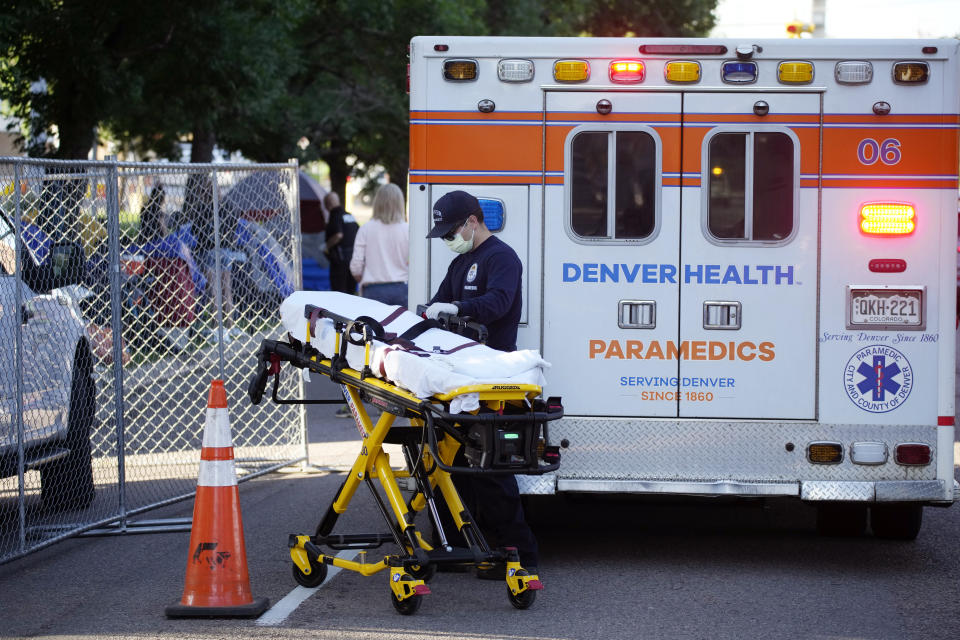 A paramedic from Denver Health wheels a gurney from an ambulance to tend to a homeless man Wednesday, July 7, 2021, during a city-sponsored carried out on an encampment of individuals living along Grant Street at Sixth Avenue south of downtown Denver. (AP Photo/David Zalubowski)