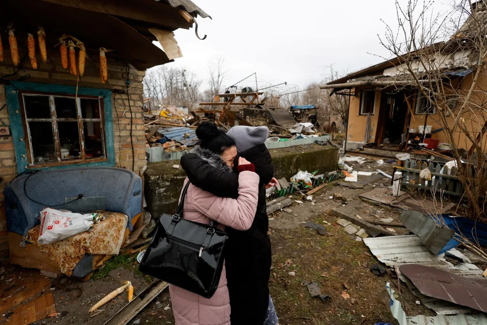 Local resident Yana embraces a friend as they stand next to her mother's house, which was damaged during a Russian missile strike in Kyiv