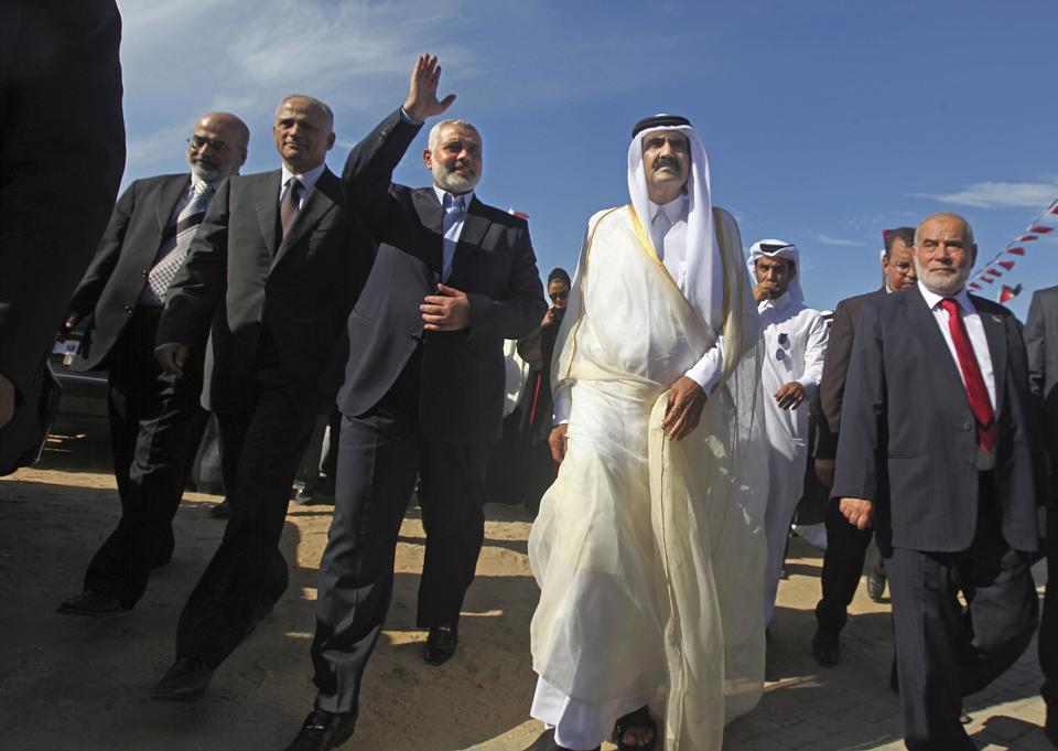 FILE - Then-Emir of Qatar Sheik Hamad bin Khalifa al-Thani, center right, and then Gaza's Hamas Prime minister Ismail Haniyeh, third left, arrive for the corner-stone laying ceremony of a center providing artificial limbs, in Bait Lahiya, northern Gaza Strip, Oct. 23, 2012. For decades, Doha has flung open its doors to Taliban warlords, Islamist dissidents, African rebel commanders and exiles of every stripe. (AP Photo/Ali Ali, Pool, File)