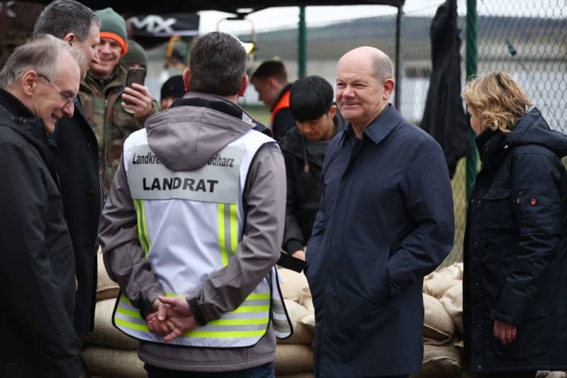 German Chancellor Olaf Scholz (C) in conversation with Andre Schroeder, District Administrator of Mansfeld-Suedharz, during a visit to the central sandbag filling facility in Berga. On the same day, Chancellor Scholz and Saxony-Anhalt's Minister President Haseloff will visit the flood area around the Helme and talk to volunteers. Jan Woitas/dpa