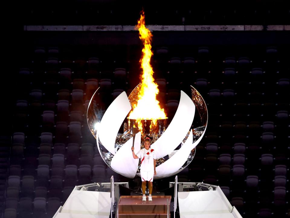 Naomi Osaka of Team Japan lights the Olympic cauldron with the Olympic torch during the opening ceremony at an empty Olympic Stadium.