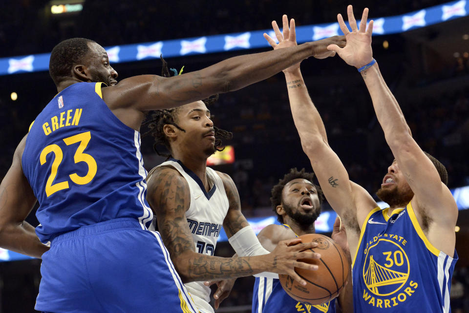 Memphis Grizzlies guard Ja Morant, second from left, handles the ball against Golden State Warriors forward Draymond Green (23), guard Stephen Curry (30), and forward Andrew Wiggins, second from right, in the first half during Game 1 of a second-round NBA basketball playoff series Sunday, May 1, 2022, in Memphis, Tenn. (AP Photo/Brandon Dill)